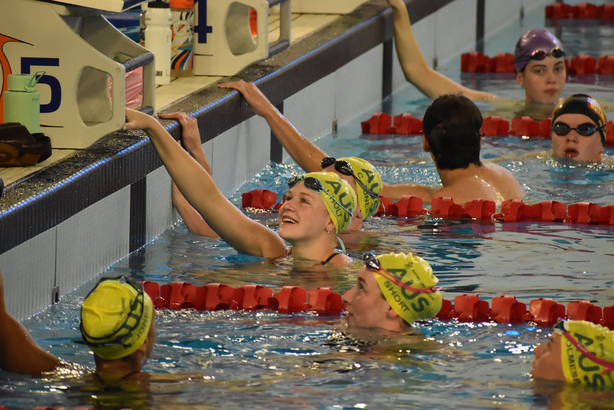A photo of an Australian women's Relay Team with all four swimmers in the water. They are wearing Australian swimming caps.