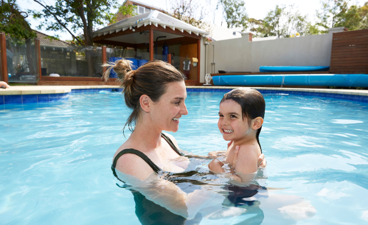 Mother holding 4 year old son in pool helping to learn to swim