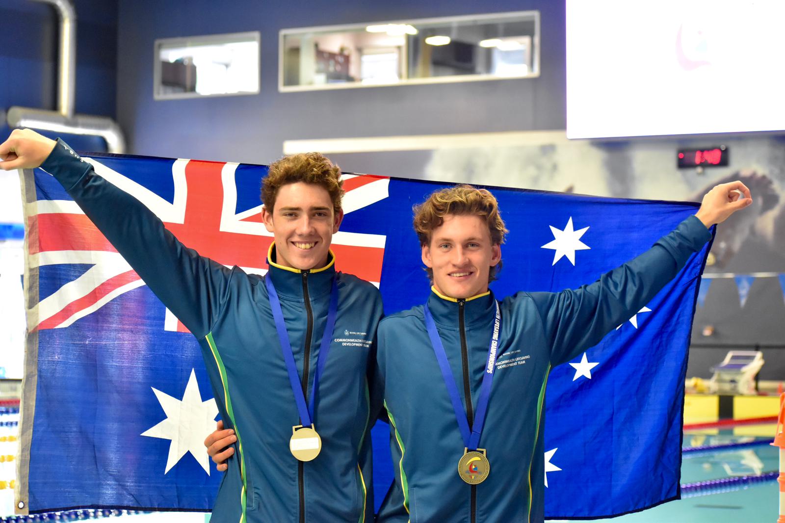 Photo of two athletes with gold medals around their neck holding an Australian flag behind them