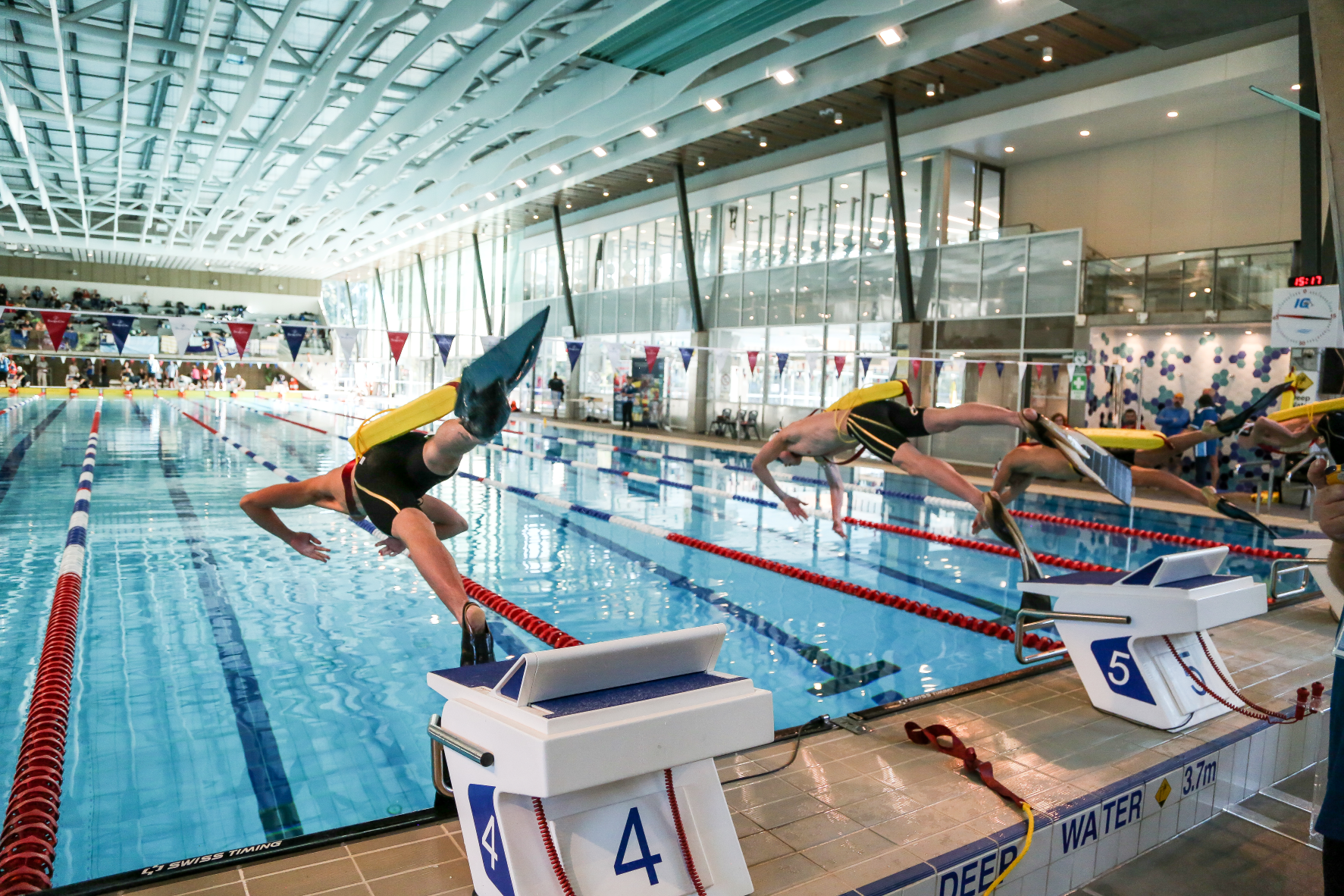 People diving into a pool with rescue tubes and fins