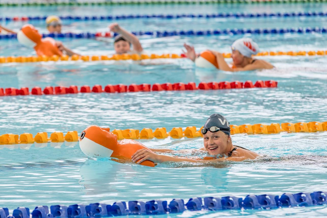 Jemma Holt in a pool holding a mannikin and smiling.